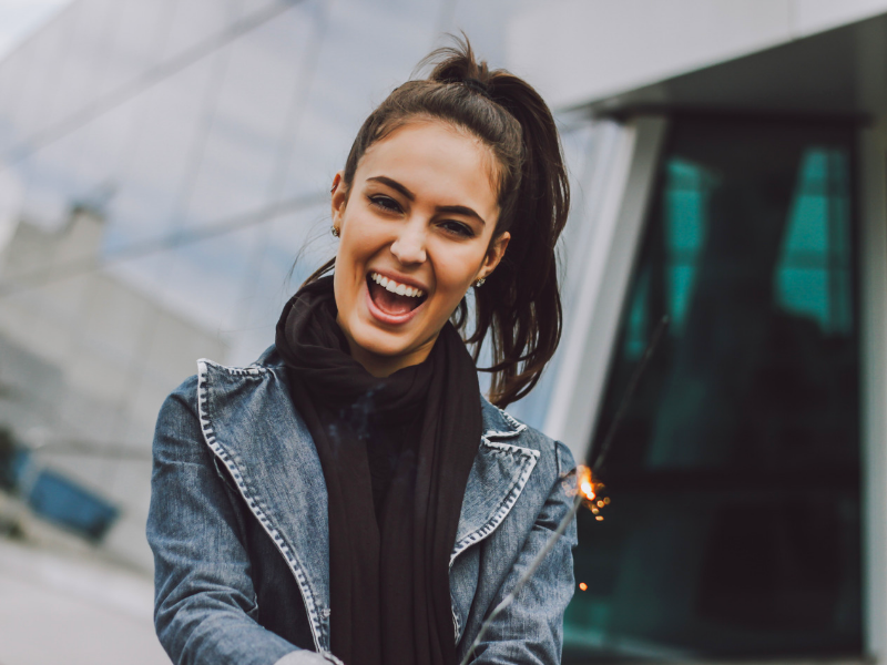 young woman with a ponytail holds a sparkler